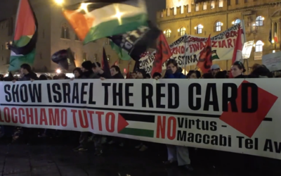 Anti-Israel protesters wave Palestinian flags and hoist a sign reading 'give Israel the red card' against Israeli participation in sporting events, outside a basketball game between Virtus Bologna and Maccabi Tel Aviv in Bologna, Italy, November 21, 2025. (Screen capture: Il Fatto Quotidiano)